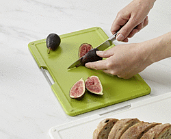 Frau die auf einem grünem Schneidebrett Feigen schneidet