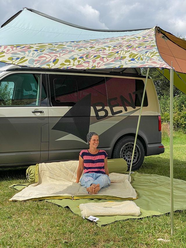 Grüne Kissenrollen vor Van. Frau sitzt auf der Kissenrolle