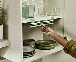 Frau die sich ein Schneidebrett aus dem Unterregal rausholt