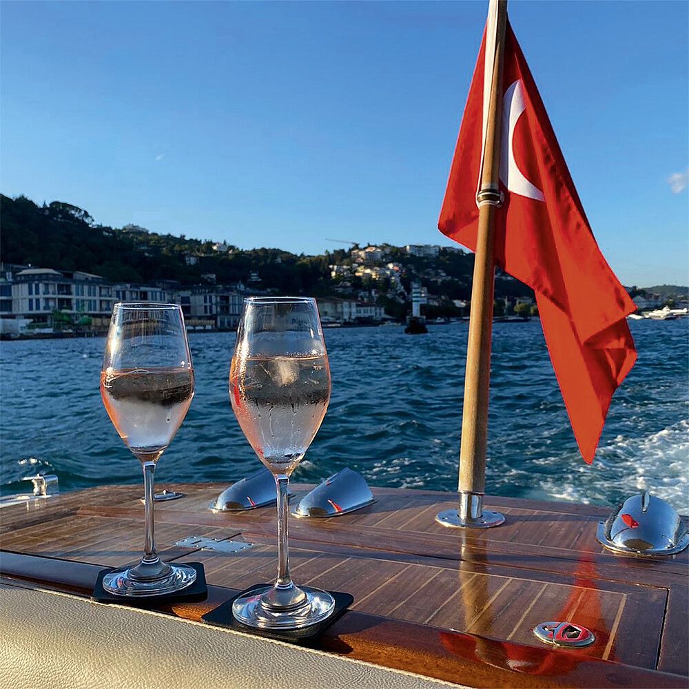 998454723 Silwy Magnet-Kristallgläser Champagner auf einem Boot abgestellt. Rote Flagge am Boot montiert und Wasser mit Landschaft im Hintergrund
