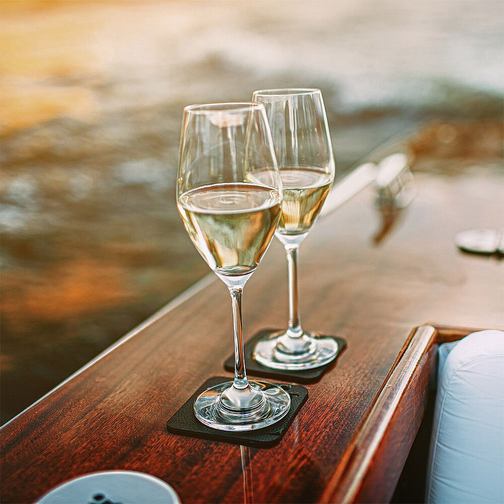 998454721 Silwy Magnet-Kristallgläser Champagner auf einem Boot abgestellt. Im Hintergrund verschwommen Wasser