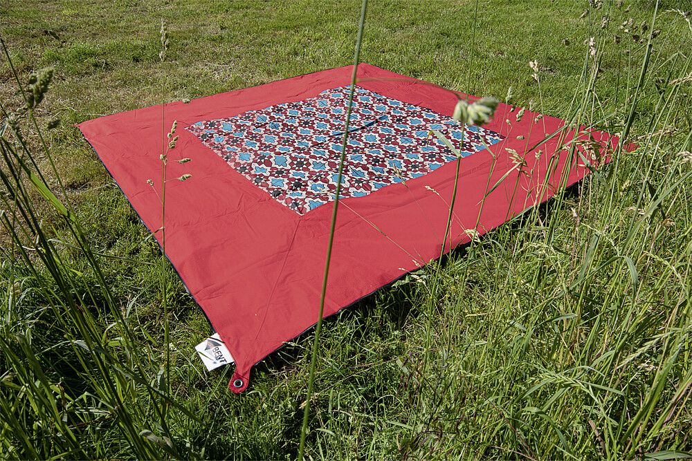 BENT Teppich , rot mit Muster in der Mitte, auf einer Wiese
