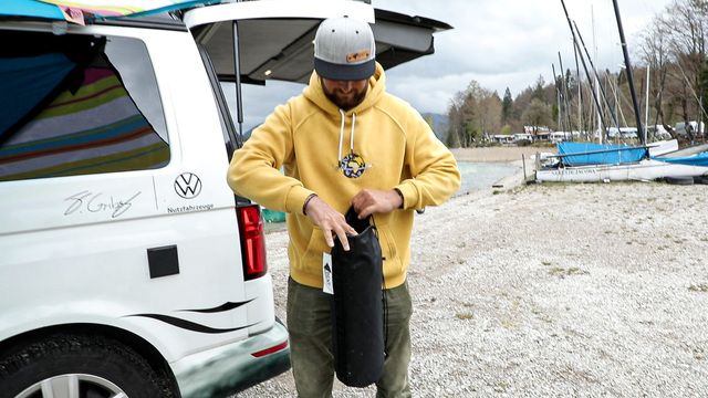 Mann vor Auto mit eingeapckter Decke